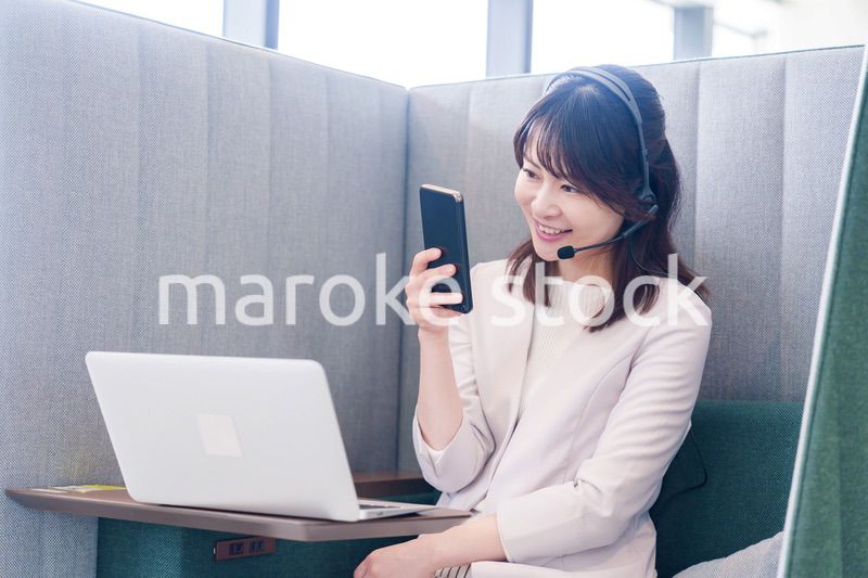 リモート会議をサボってスマホを使う若いビジネスパーソン