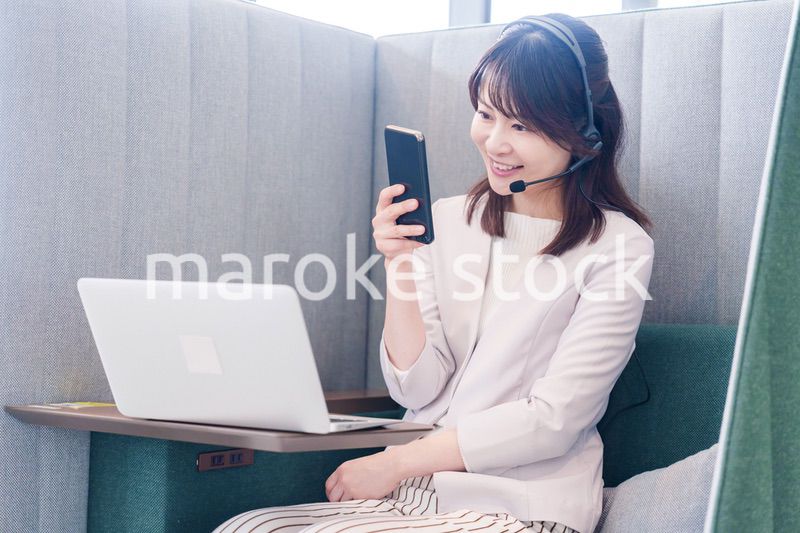 リモート会議をサボってスマホを使う若いビジネスパーソン