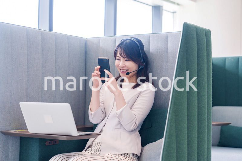 リモート会議をサボってスマホを使う若いビジネスパーソン