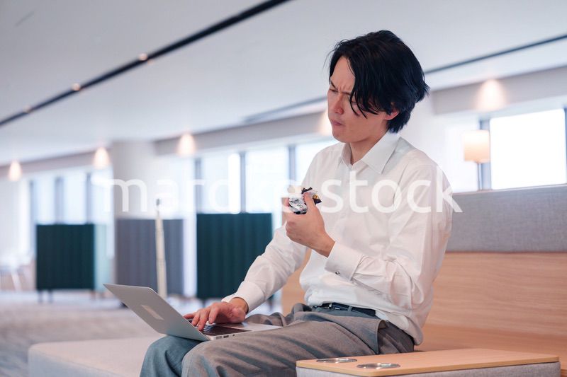 お昼ごはんを食べながらオフィスで仕事をする男性