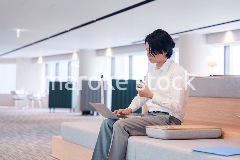 お昼ごはんを食べながらオフィスで仕事をする男性