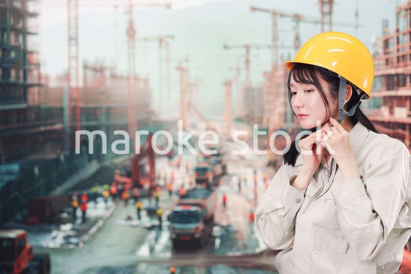 建設現場でヘルメットを装着する作業服姿の女性