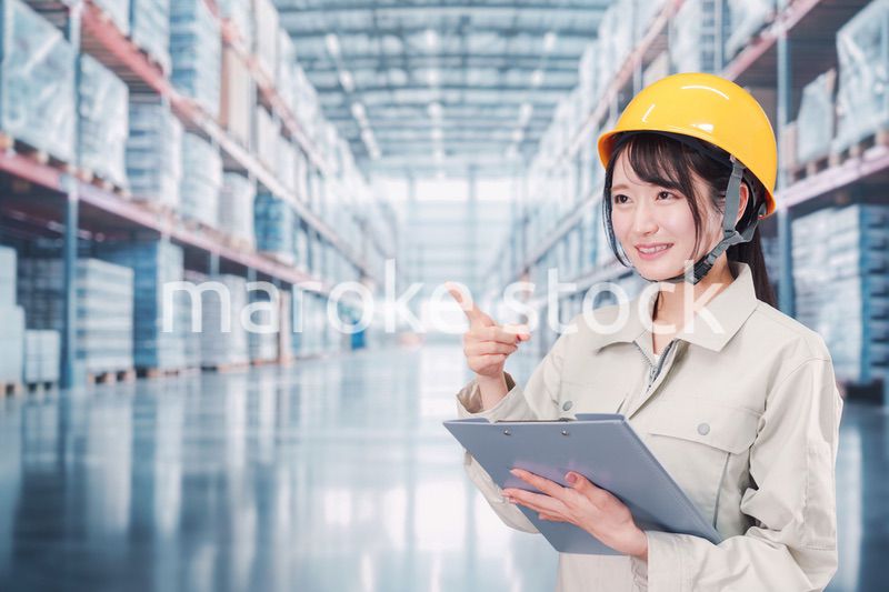 大きな物流倉庫で働くヘルメットを被った若い女性