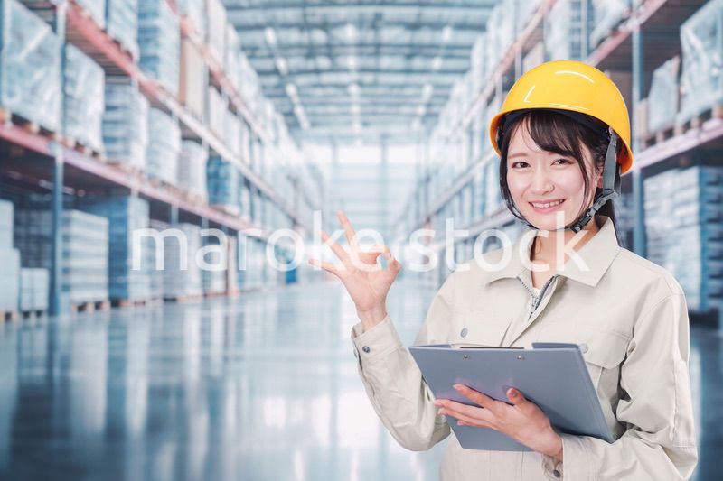 大きな物流倉庫で働くヘルメットを被った若い女性