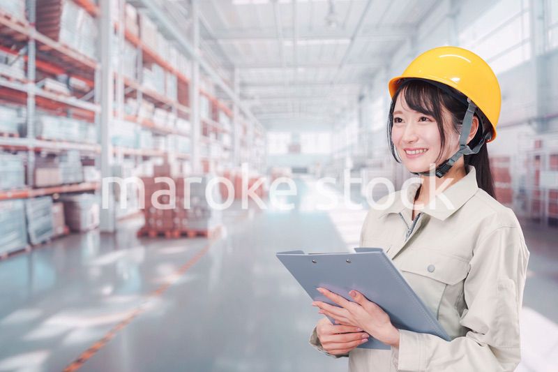 大きな物流倉庫で働くヘルメットを被った若い女性