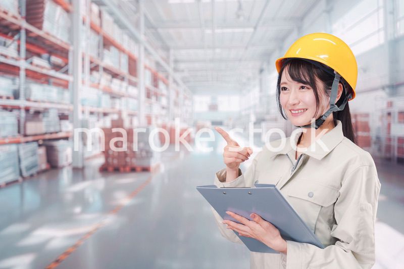 大きな物流倉庫で働くヘルメットを被った若い女性
