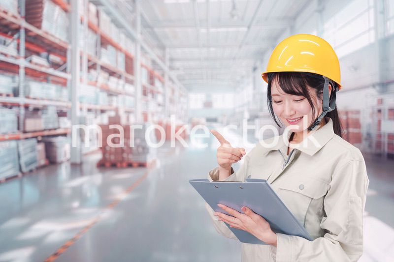 大きな物流倉庫で働くヘルメットを被った若い女性