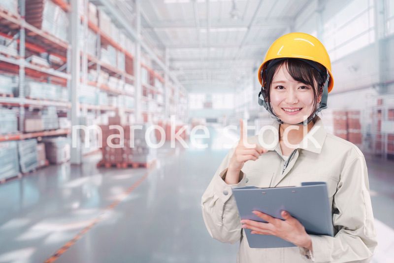 大きな物流倉庫で働くヘルメットを被った若い女性