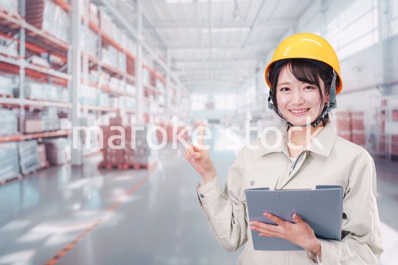 大きな物流倉庫で働くヘルメットを被った若い女性