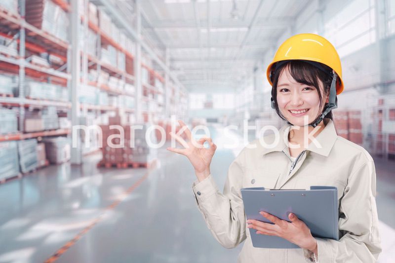 大きな物流倉庫で働くヘルメットを被った若い女性