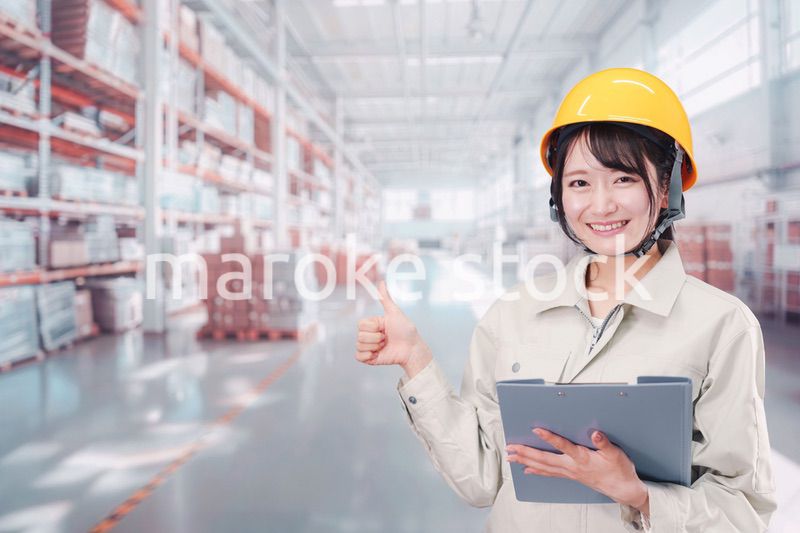 大きな物流倉庫で働くヘルメットを被った若い女性