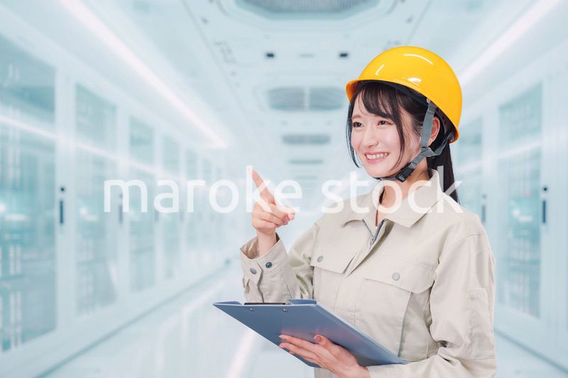 データセンターのサーバールームで働く作業服姿の女性