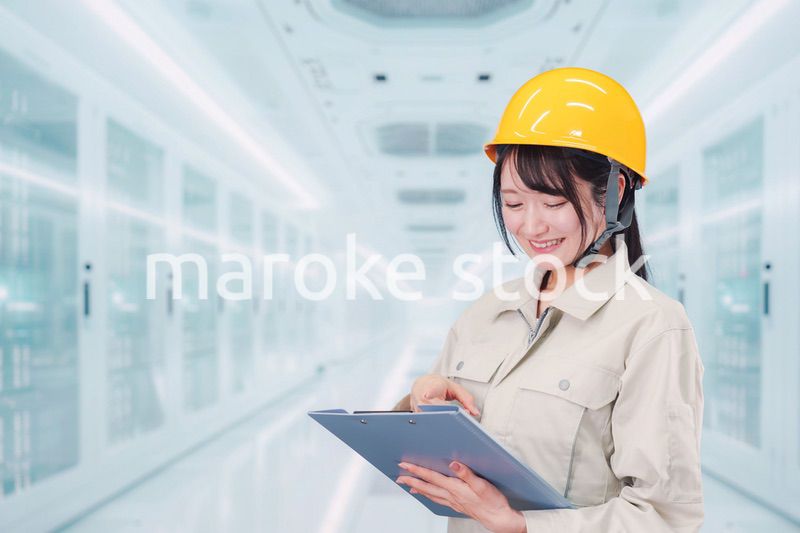 データセンターのサーバールームで働く作業服姿の女性