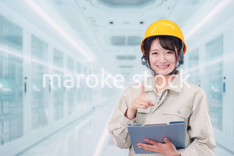 データセンターのサーバールームで働く作業服姿の女性