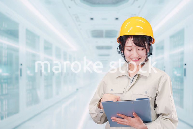 データセンターのサーバールームで働く作業服姿の女性