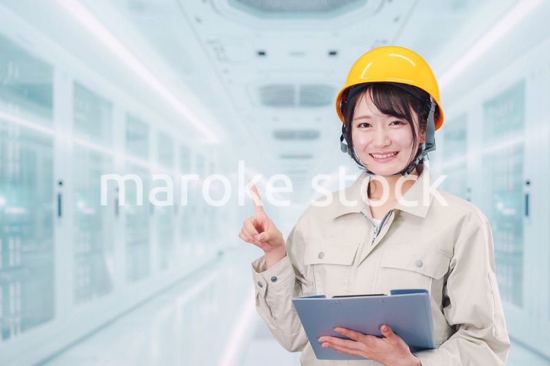 データセンターのサーバールームで働く作業服姿の女性
