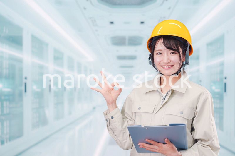 データセンターのサーバールームで働く作業服姿の女性