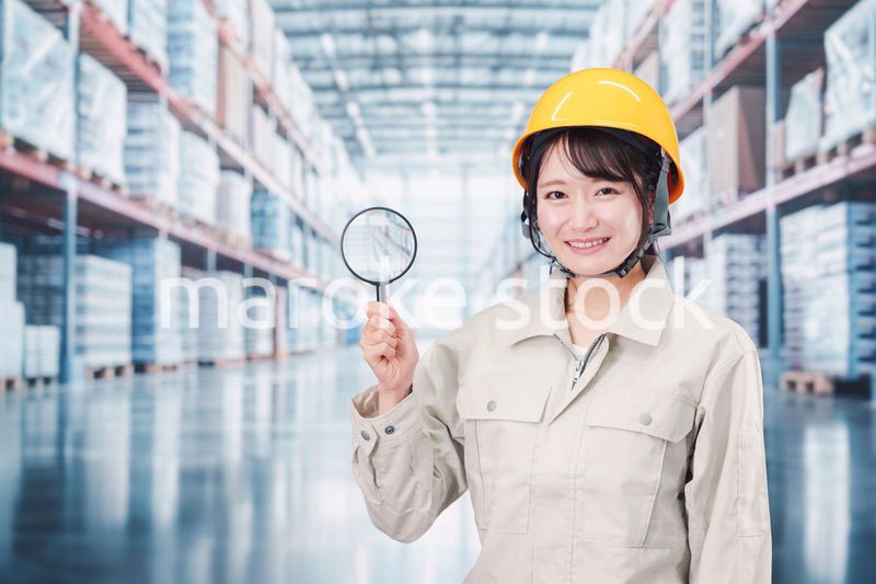 倉庫で在庫を探す作業服姿の女性
