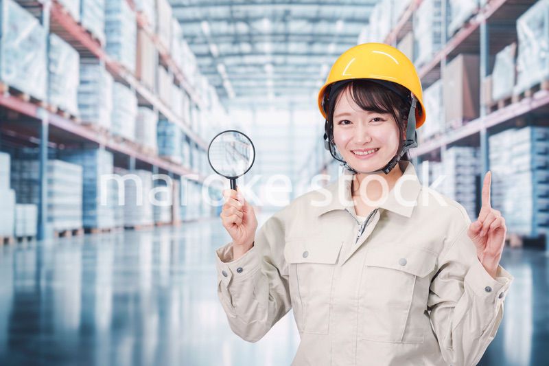 倉庫で在庫を探す作業服姿の女性