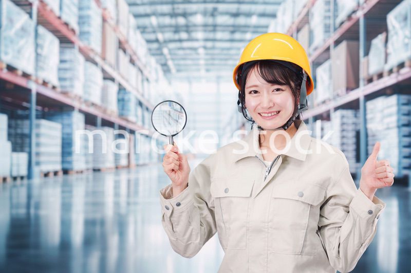 倉庫で在庫を探す作業服姿の女性