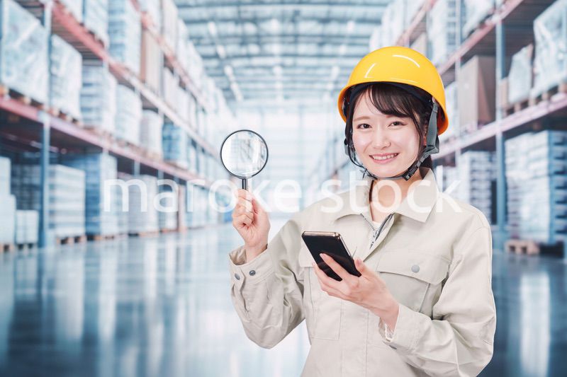 倉庫で在庫を探す作業服姿の女性