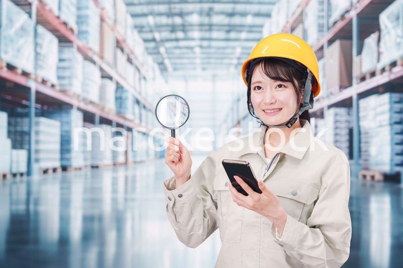 倉庫で在庫を探す作業服姿の女性