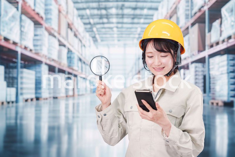 倉庫で在庫を探す作業服姿の女性