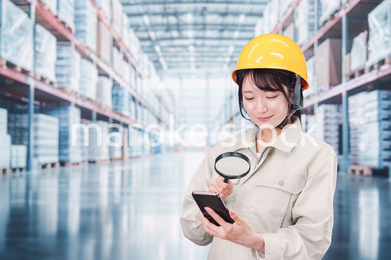 倉庫で在庫を探す作業服姿の女性