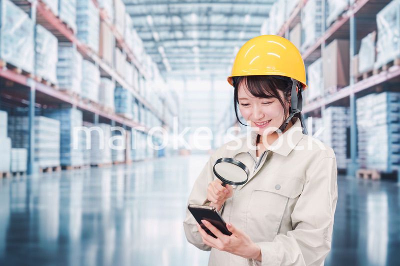 倉庫で在庫を探す作業服姿の女性
