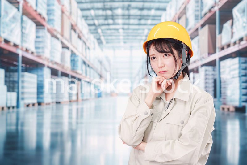 倉庫の中で頭を抱える女性の従業員