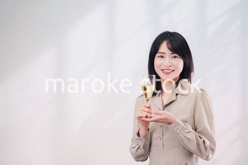 笑顔でスパークリングワインを飲む若い女性（シンプル背景）