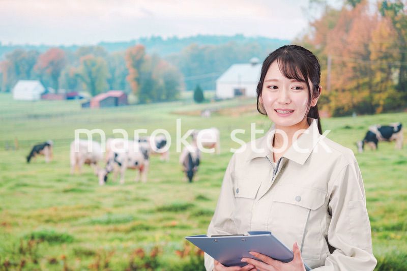 牧場で働く作業服姿の若い女性
