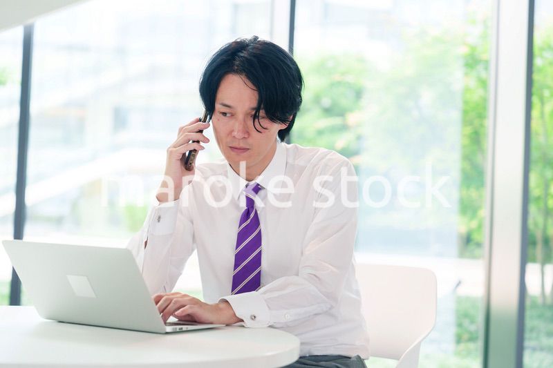 不機嫌な表情で電話をするビジネスマン