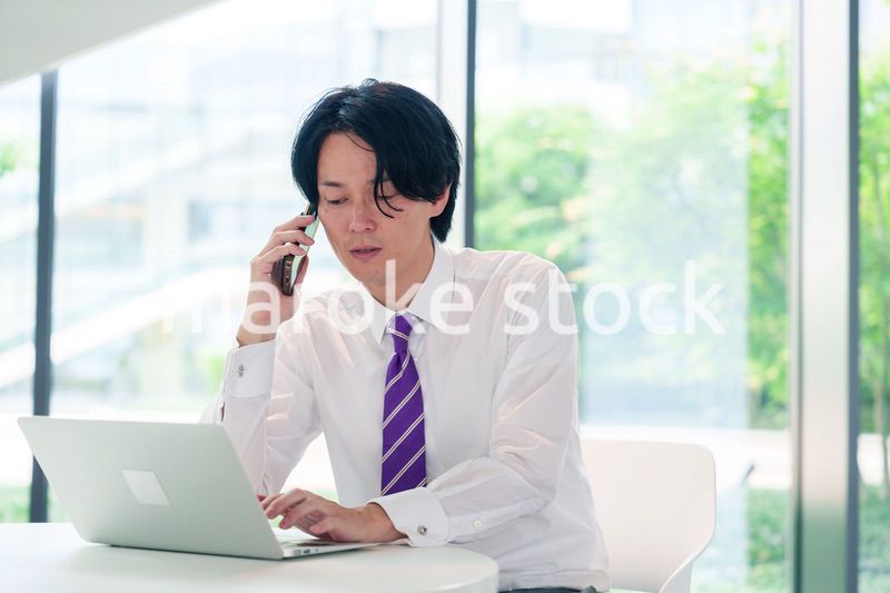 不機嫌な表情で電話をするビジネスマン