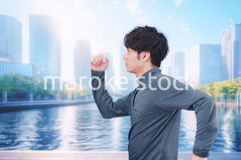 お昼の都会でランニングをする若い男性