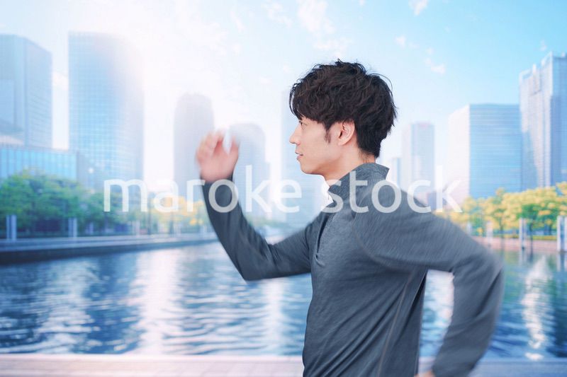 お昼の都会でランニングをする若い男性