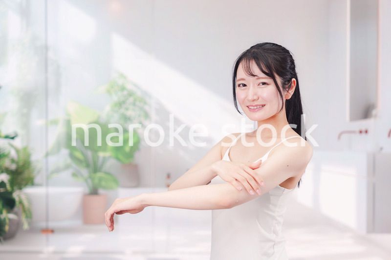 腕にクリームを塗る若い女性