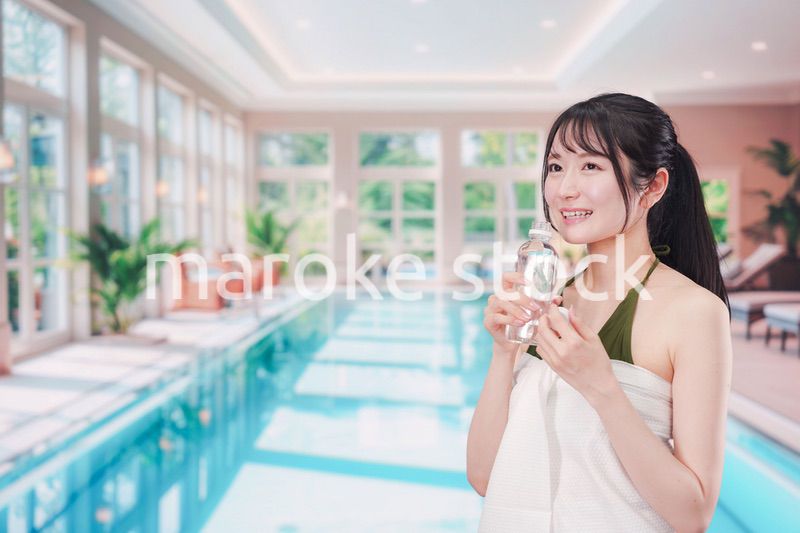 プールで水を飲んでクールダウンする水着姿の女性