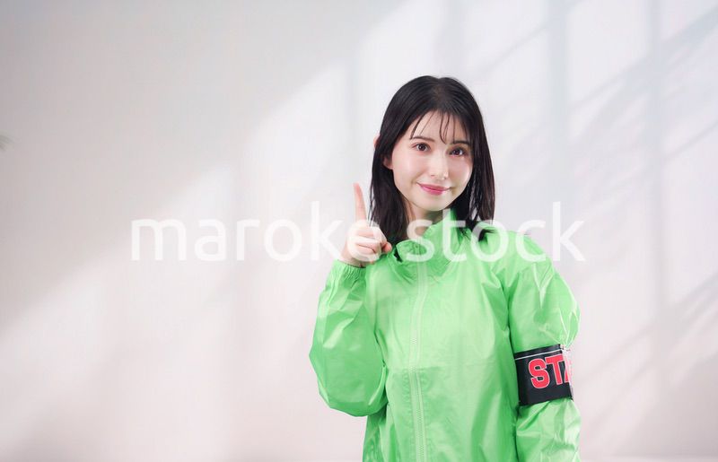 スタッフジャンパーをきた笑顔のイベントスタッフ（シンプル背景）