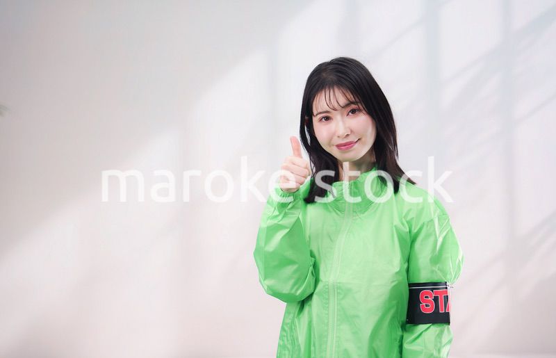 スタッフジャンパーをきた笑顔のイベントスタッフ（シンプル背景）