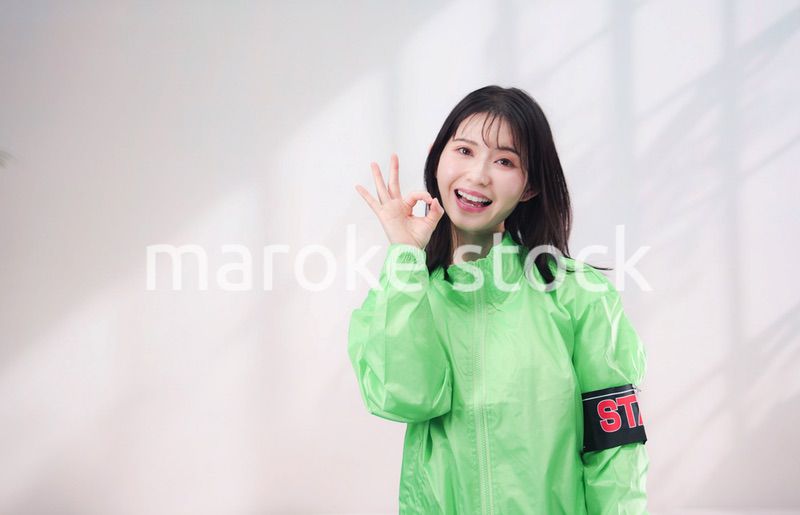 スタッフジャンパーをきた笑顔のイベントスタッフ（シンプル背景）