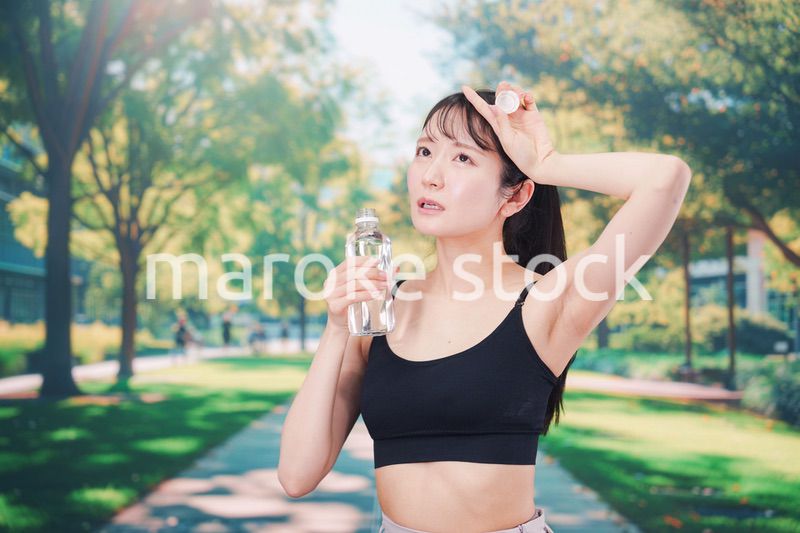 外でランニングをしながら水を飲む若い女性