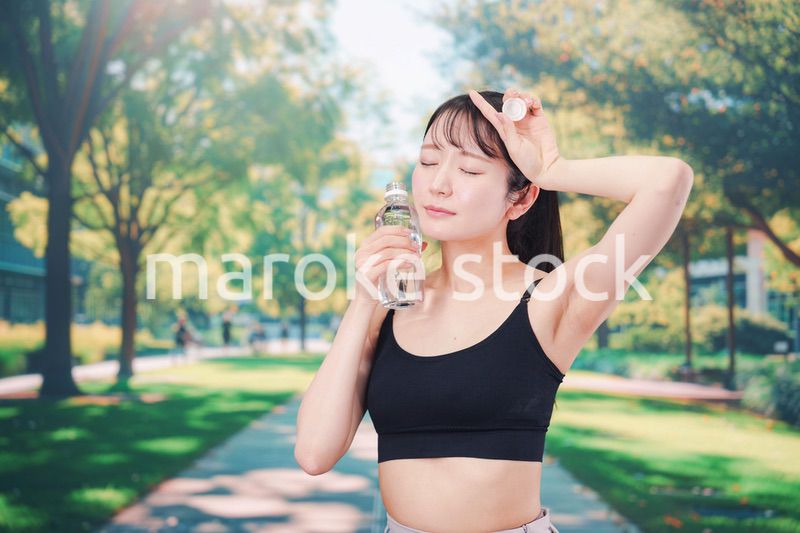 外でランニングをしながら水を飲む若い女性