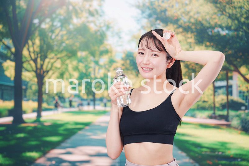 外でランニングをしながら水を飲む若い女性