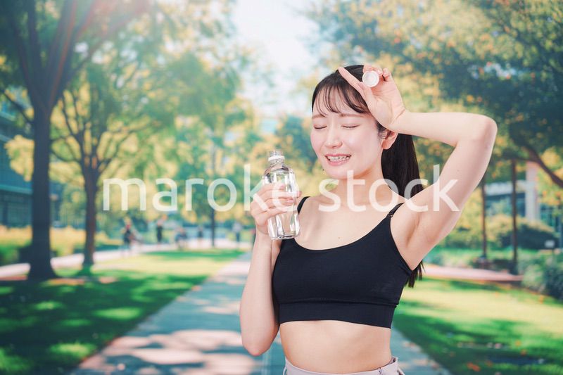 外でランニングをしながら水を飲む若い女性