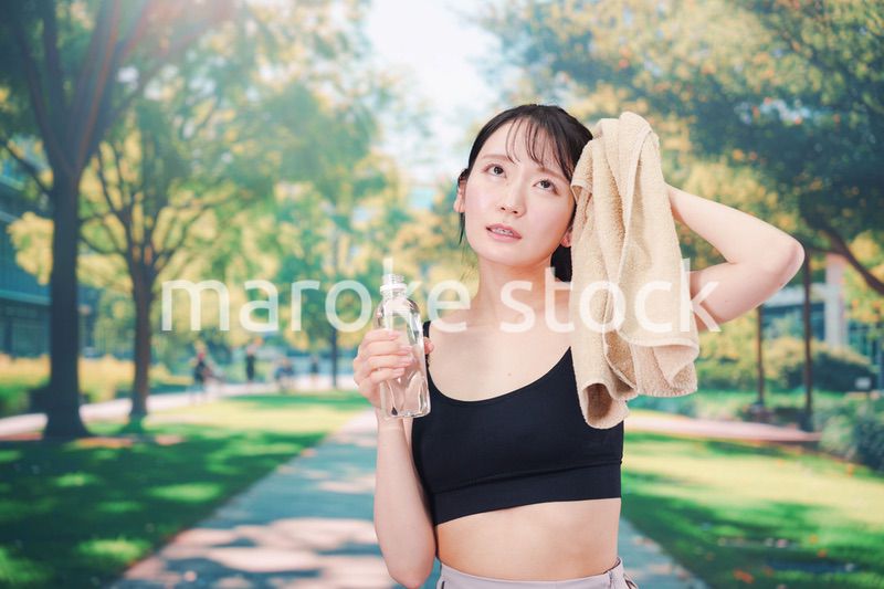 外でランニングをしながら水を飲む若い女性