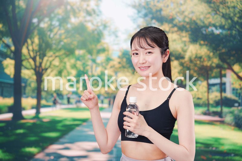 外でランニングをしながら水を飲む若い女性