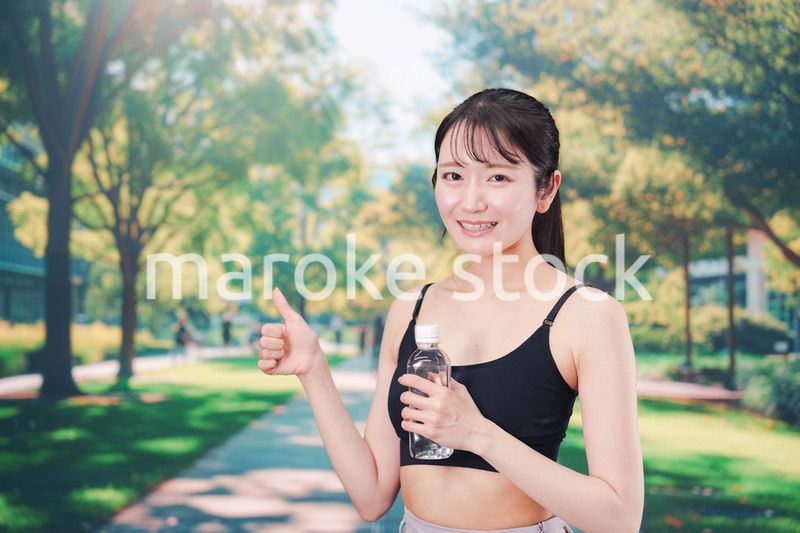 外でランニングをしながら水を飲む若い女性