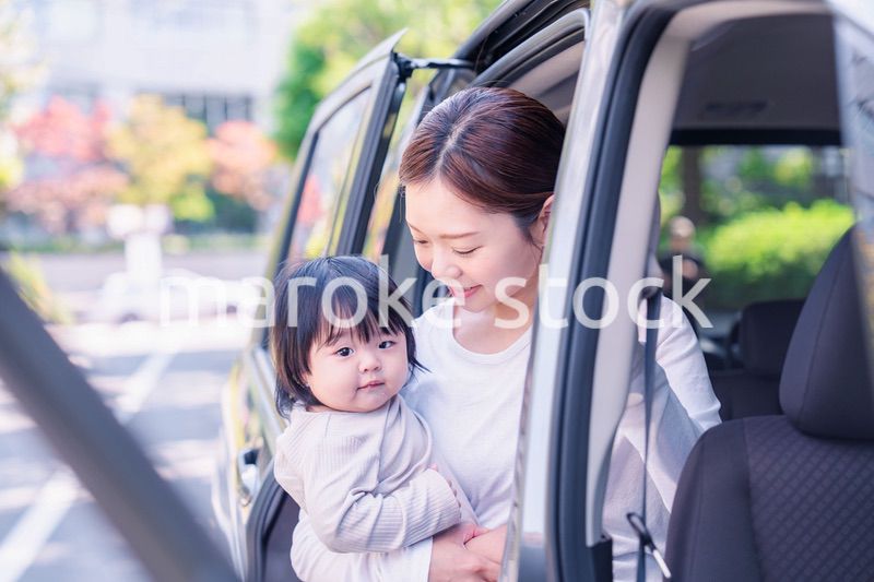 赤ちゃんと一緒に車に乗るお母さん