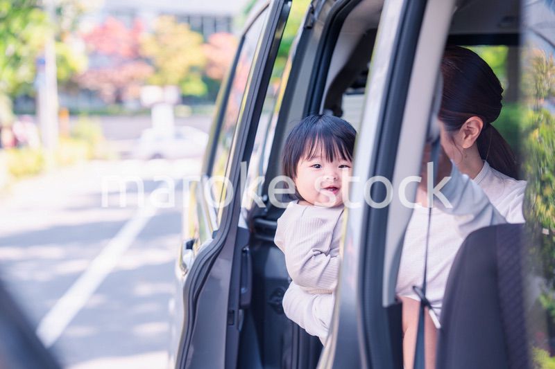 赤ちゃんと一緒に車に乗るお母さん